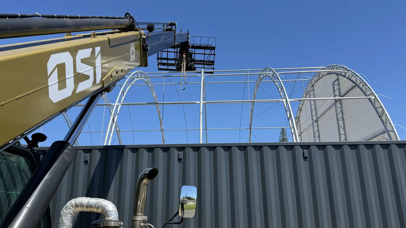 Close view of the OSI telehandler boom beside the container tent frame