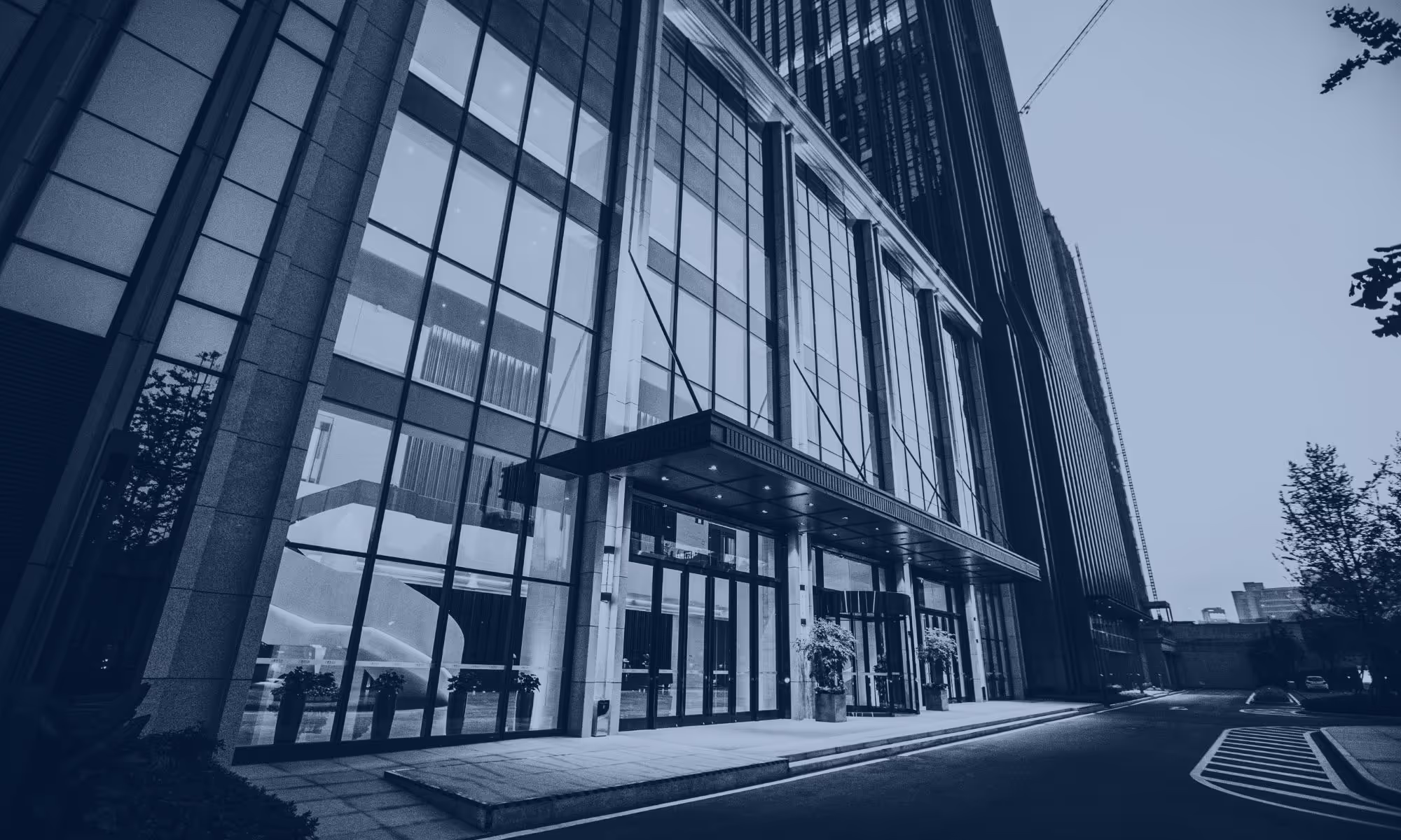 Modern commercial office building with large glass windows and entrance canopy along a quiet street.