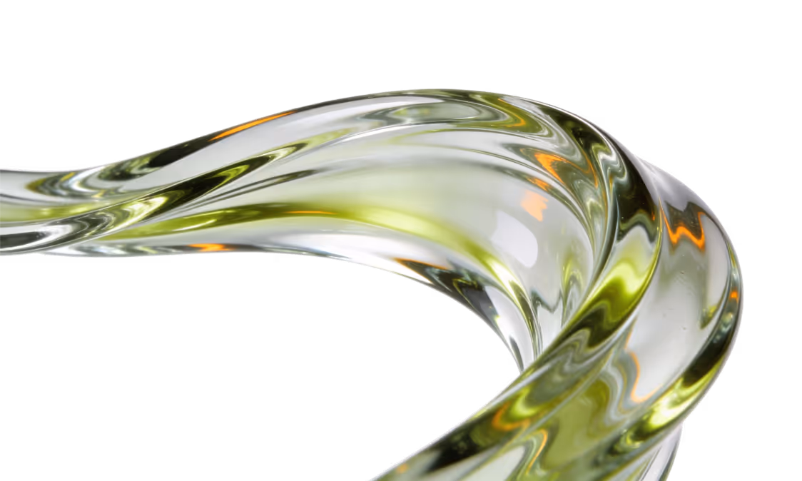 Close-up of a twisted, translucent glass sculpture with green and orange reflections.