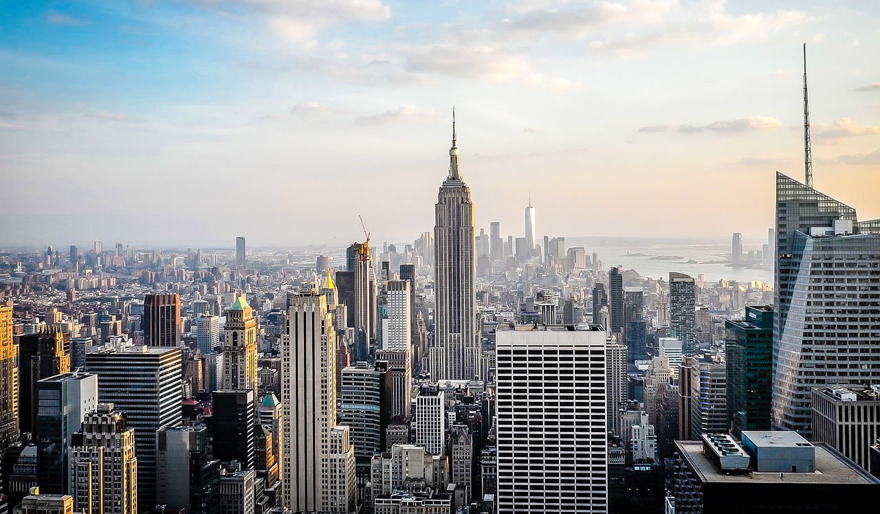 Panoramic view of New York City skyline featuring the Empire State Building at sunset with clear sky.