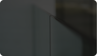 Close-up of a glass railing corner with blurred background.