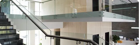 Modern indoor staircase with glass railings and black steps in a bright office or lobby area.