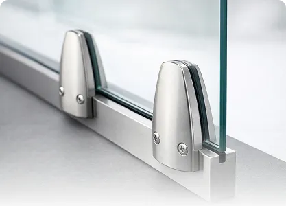 Close-up of a glass panel secured by modern stainless steel clamps on a metal base.
