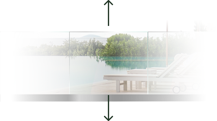 Outdoor pool area with white lounge chairs beside a glass barrier and green bushes in the background.