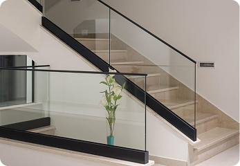 Modern indoor staircase with glass railings and a vase of white flowers at the corner.