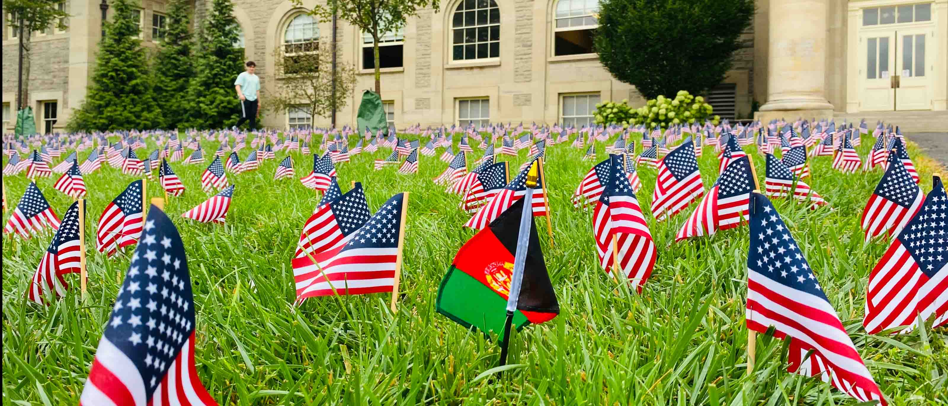 A single Afghanistan flag standing among hundreds of United States flags on the lawn at Cornell University