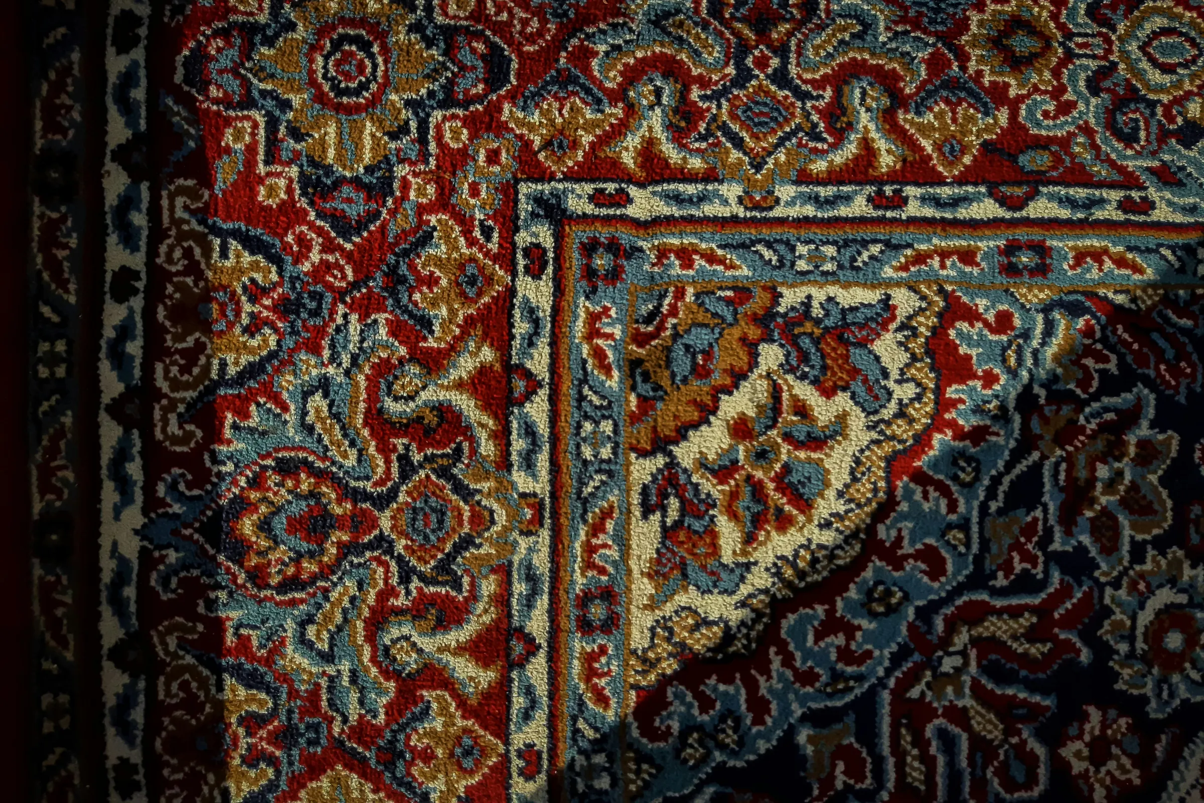 Close detail of a hand-knotted wool carpet in deep red and indigo