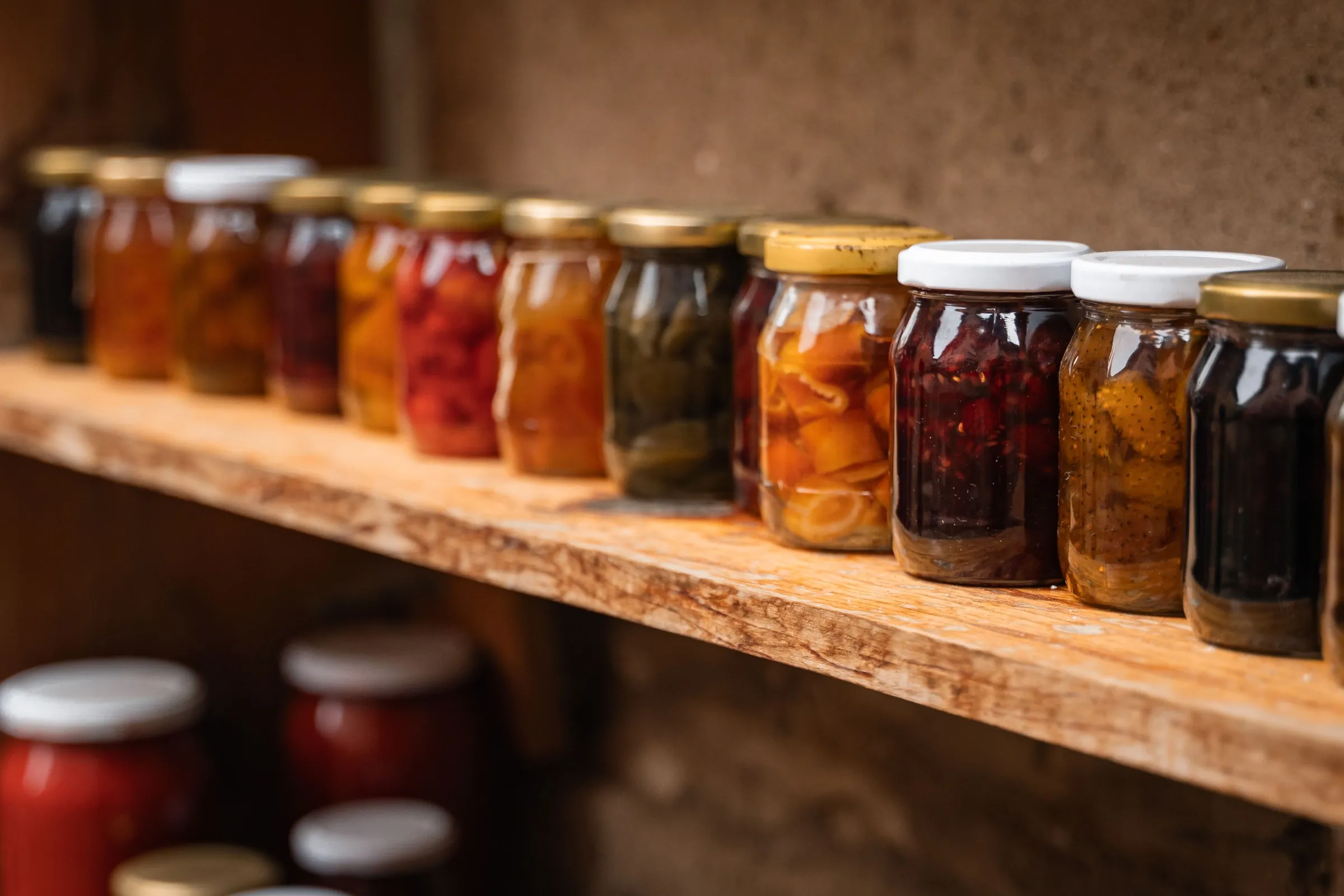 Jars of fruit preserves and honey on a shelf