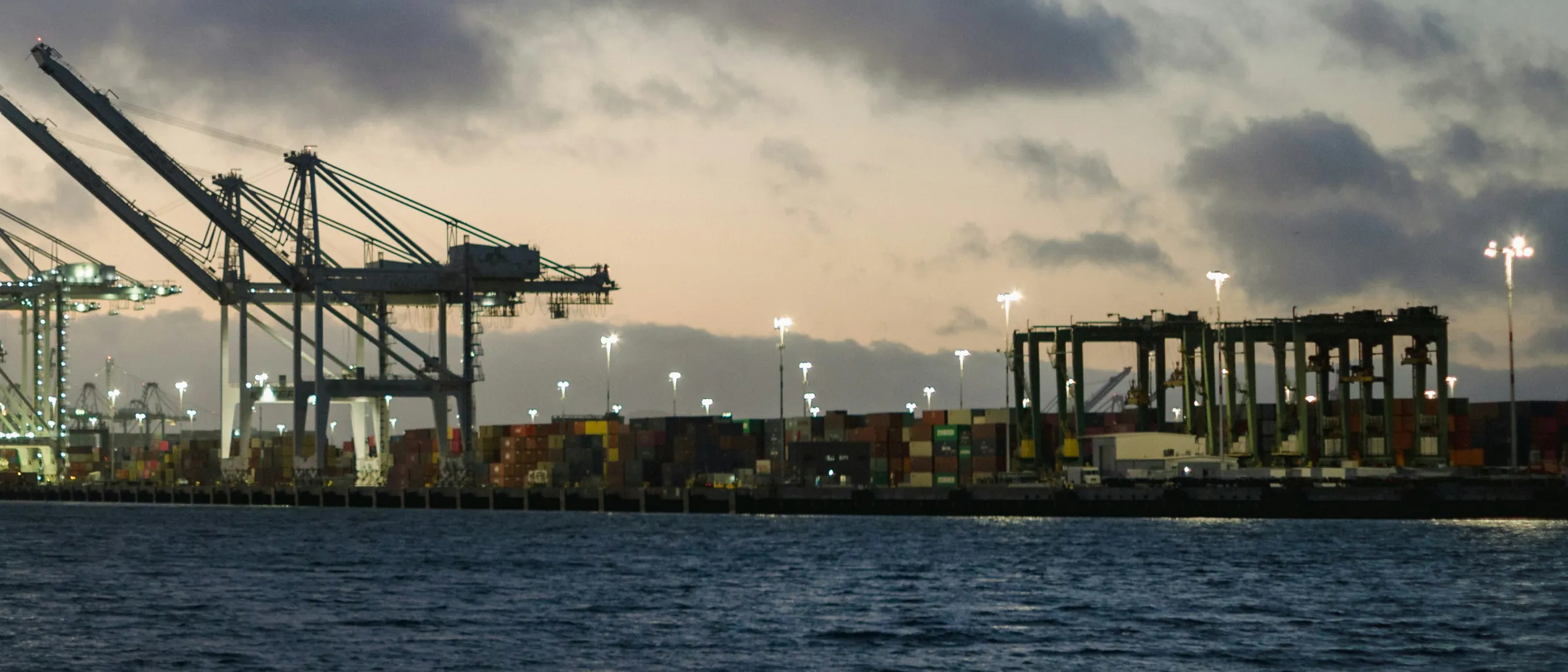 Shipping containers stacked at a port at dusk
