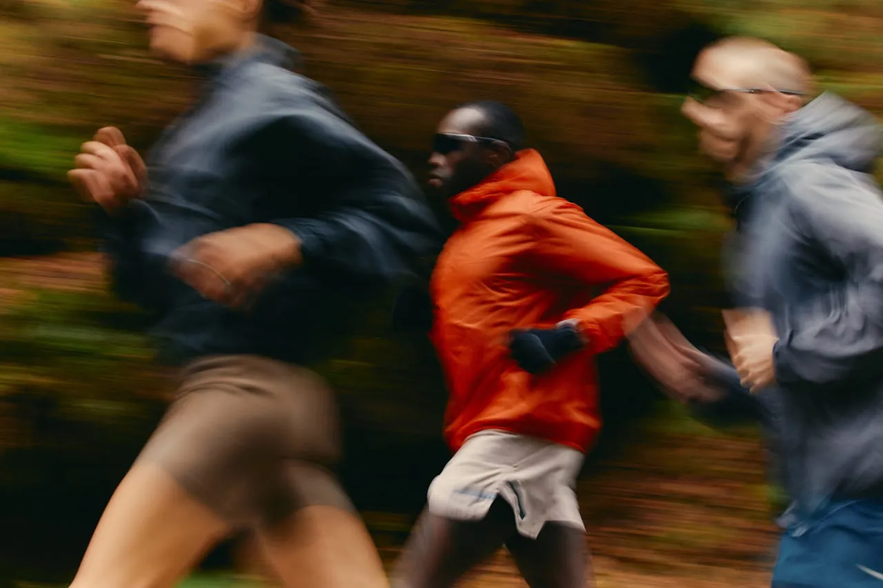 Three runners in motion wearing athletic gear, running outdoors with blurred background.