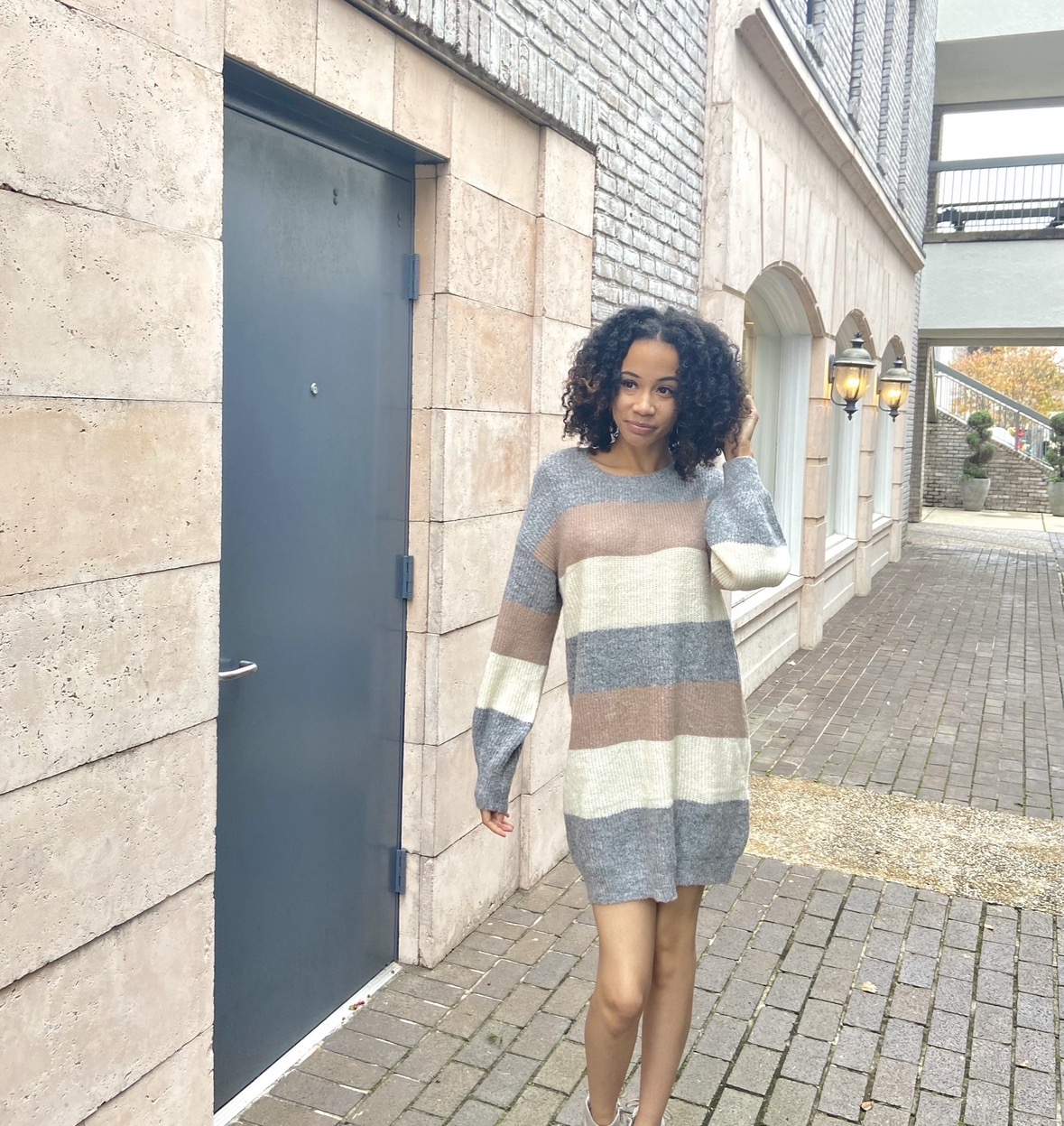 Woman smiling and taking a mirror selfie wearing a white short-sleeve nightdress in a cozy bedroom.