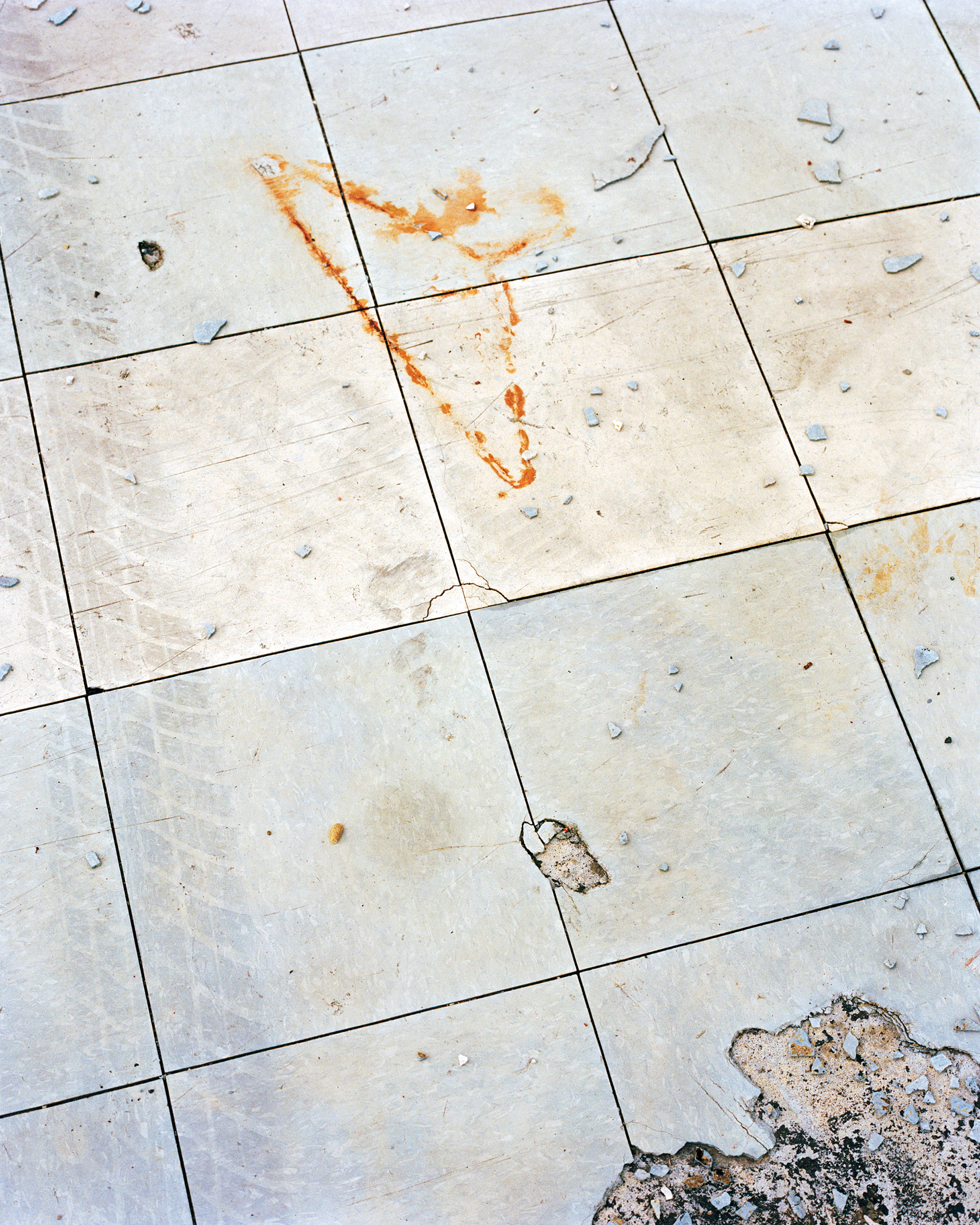 Pale tile floor scattered with debris and a rust-colored stain