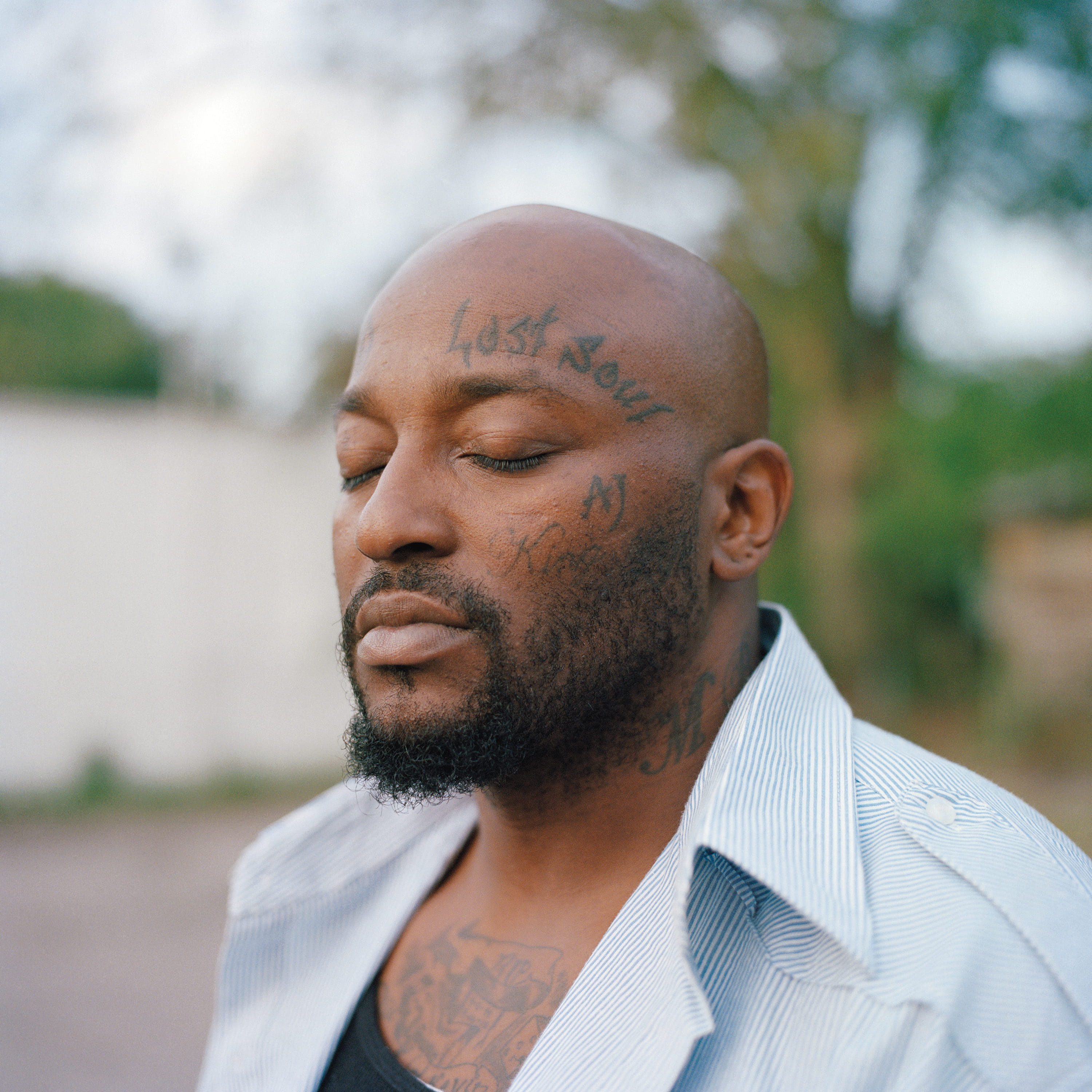 Close portrait of a man with facial tattoos, eyes closed
