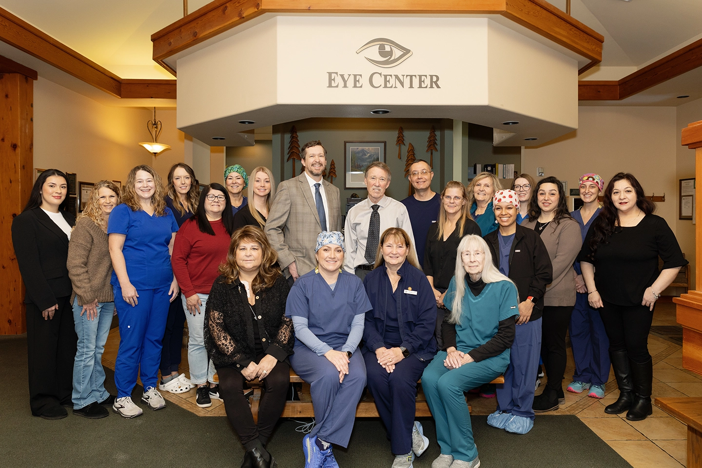 Group of medical professionals at The Eye Center in scrubs and surgical caps standing together in a clinical room with medical equipment.