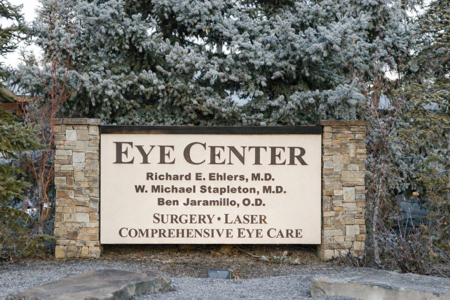 Stone-framed sign for The Eye Center listing three doctors and services including surgery, laser, and comprehensive eye care.