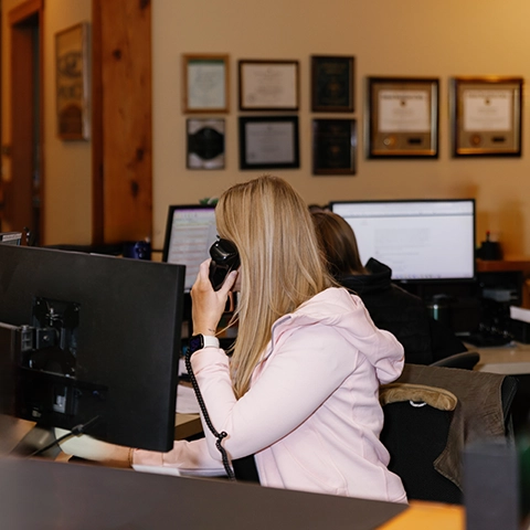 Woman operating an eye examination machine while working on a computer in The Eye Center Yakima office.