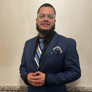 Sean Ithier smiling in a blue suit and striped tie