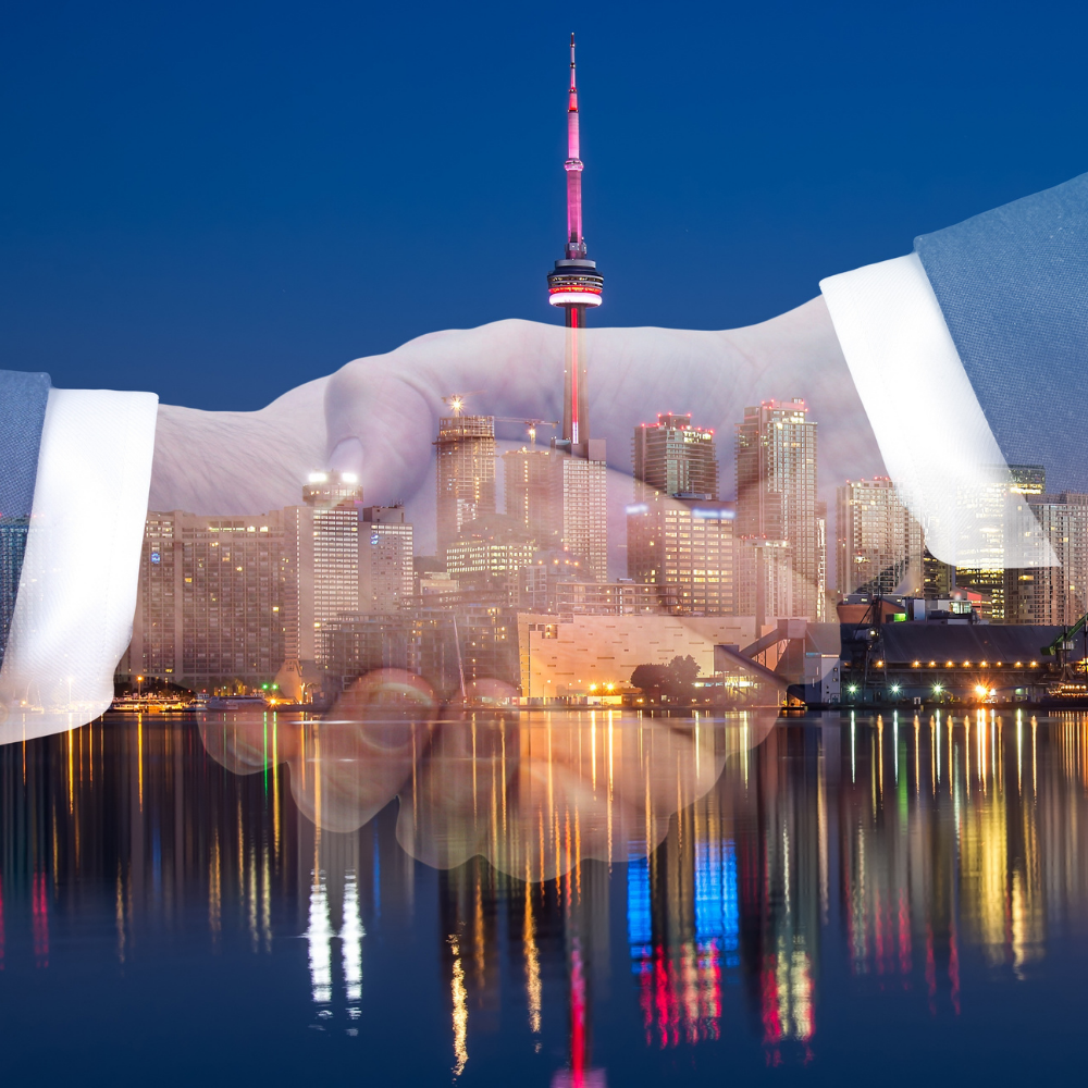 Double exposure of two business people shaking hands over a nighttime city skyline with the CN Tower illuminated.
