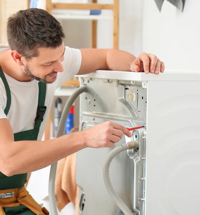 Technician using a screwdriver to repair the back of a washing machine
