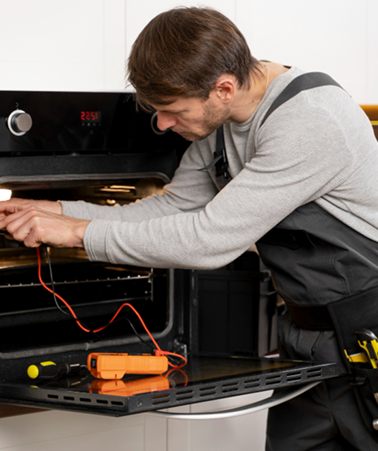 Technician repairing a dishwasher with tools from an open toolbox nearby.