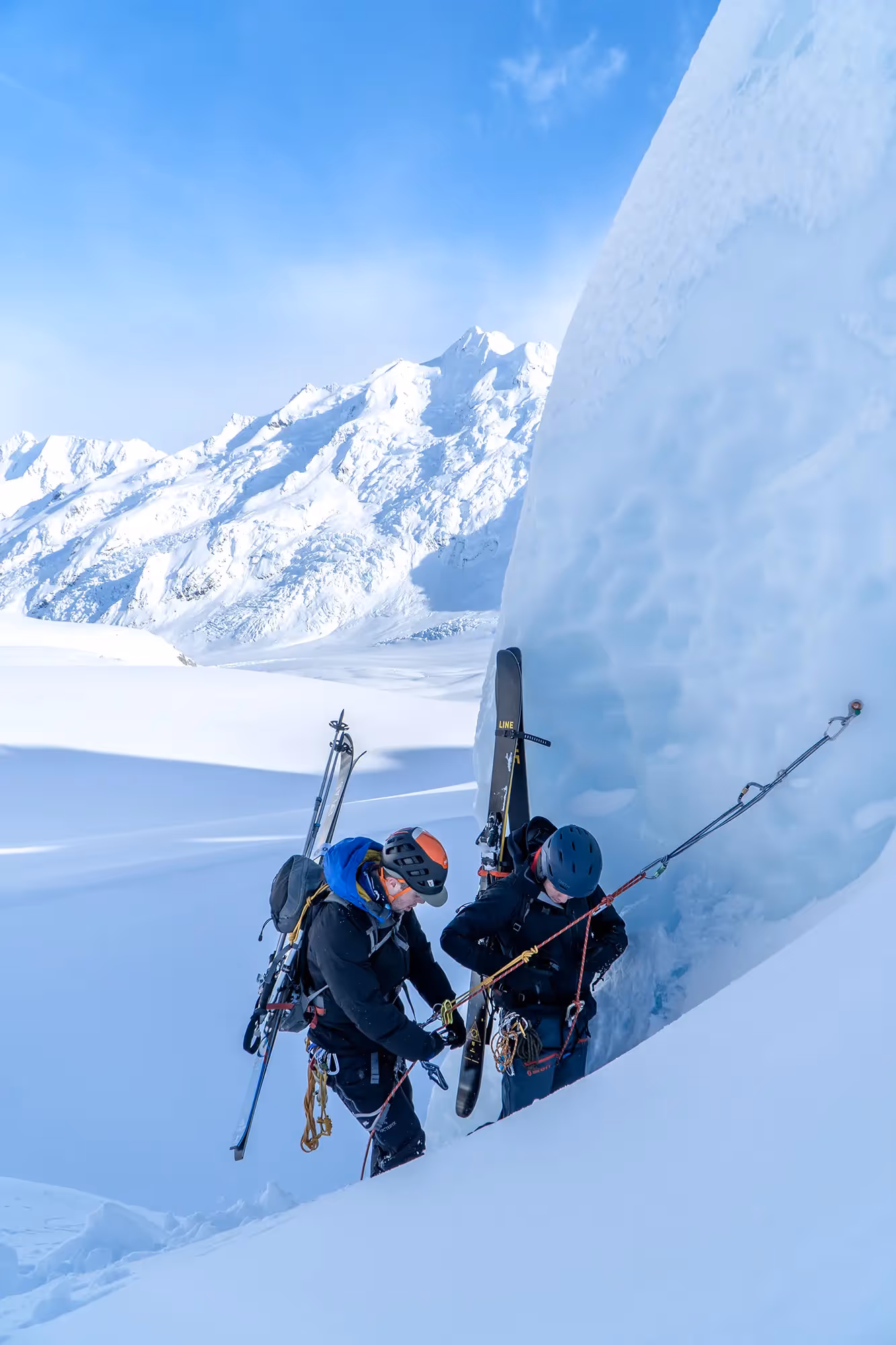 Climber ascending steep snowy slope on fixed rope