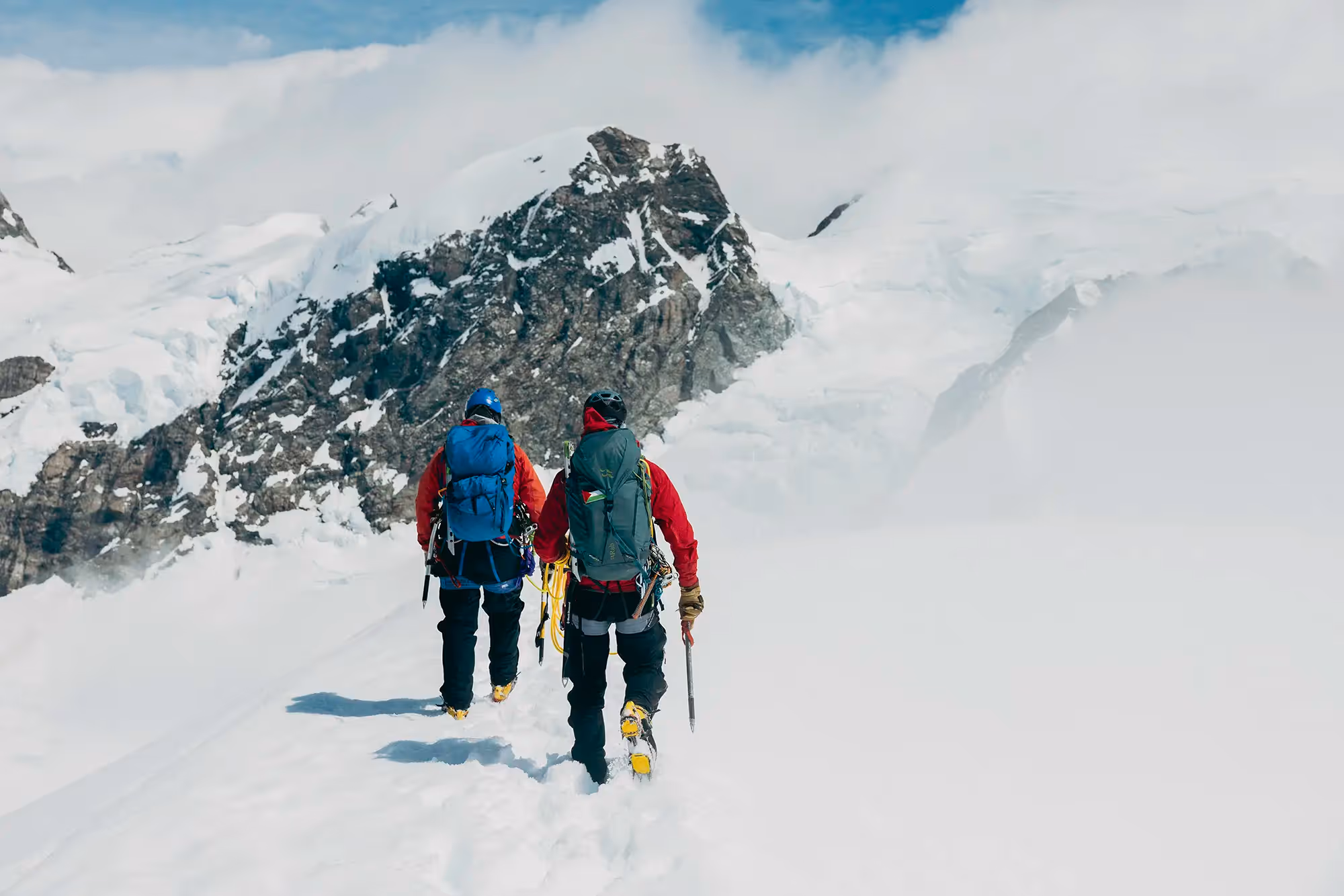 Roped climber ascending snowy alpine terrain