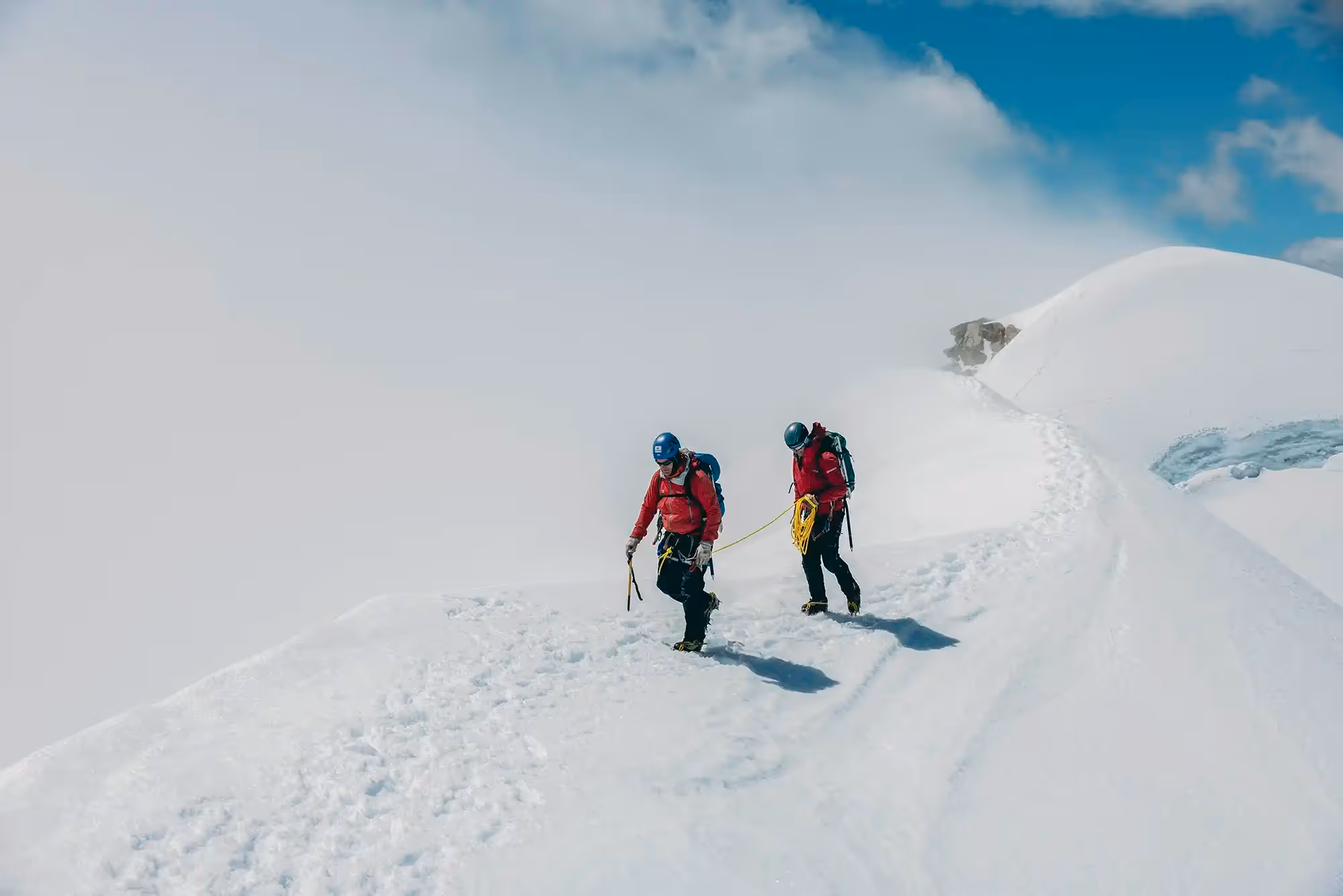 Roped climbers walking along snowy ridge