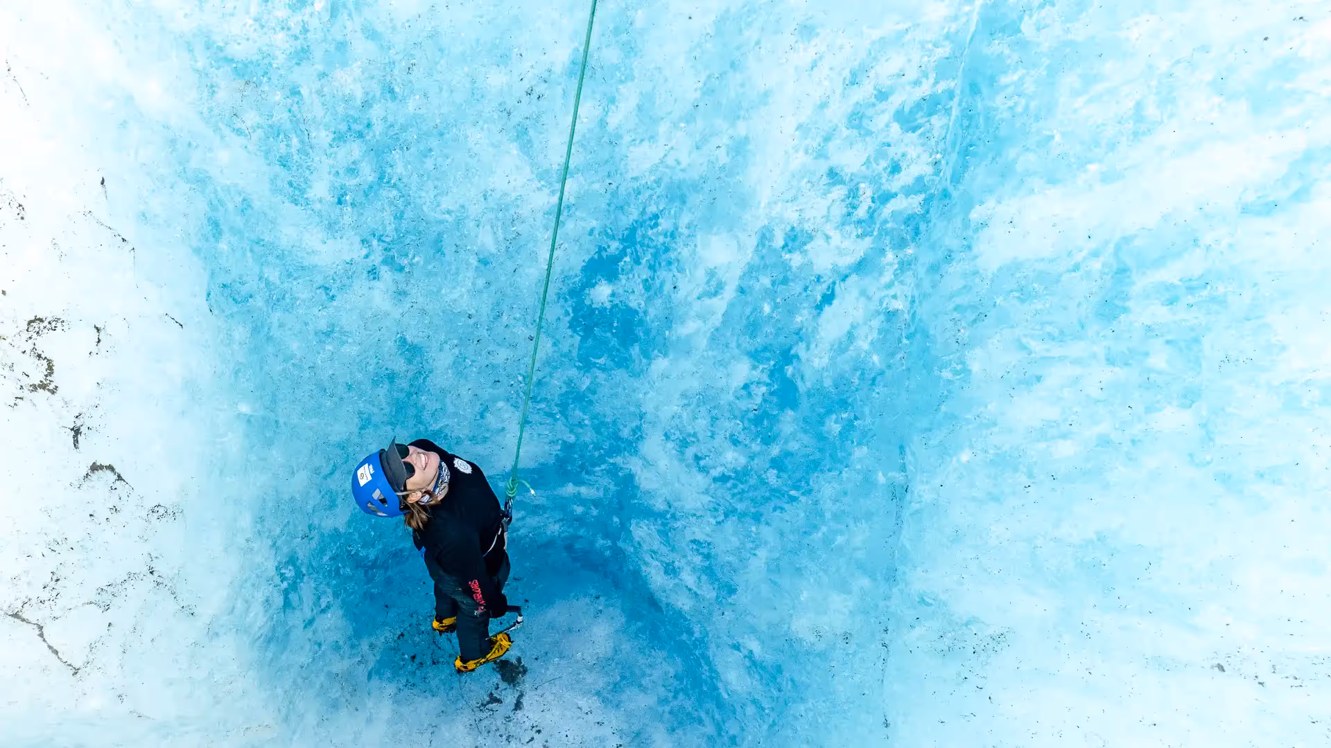 Guest inside ice hole roped up preparing to start ice climbing