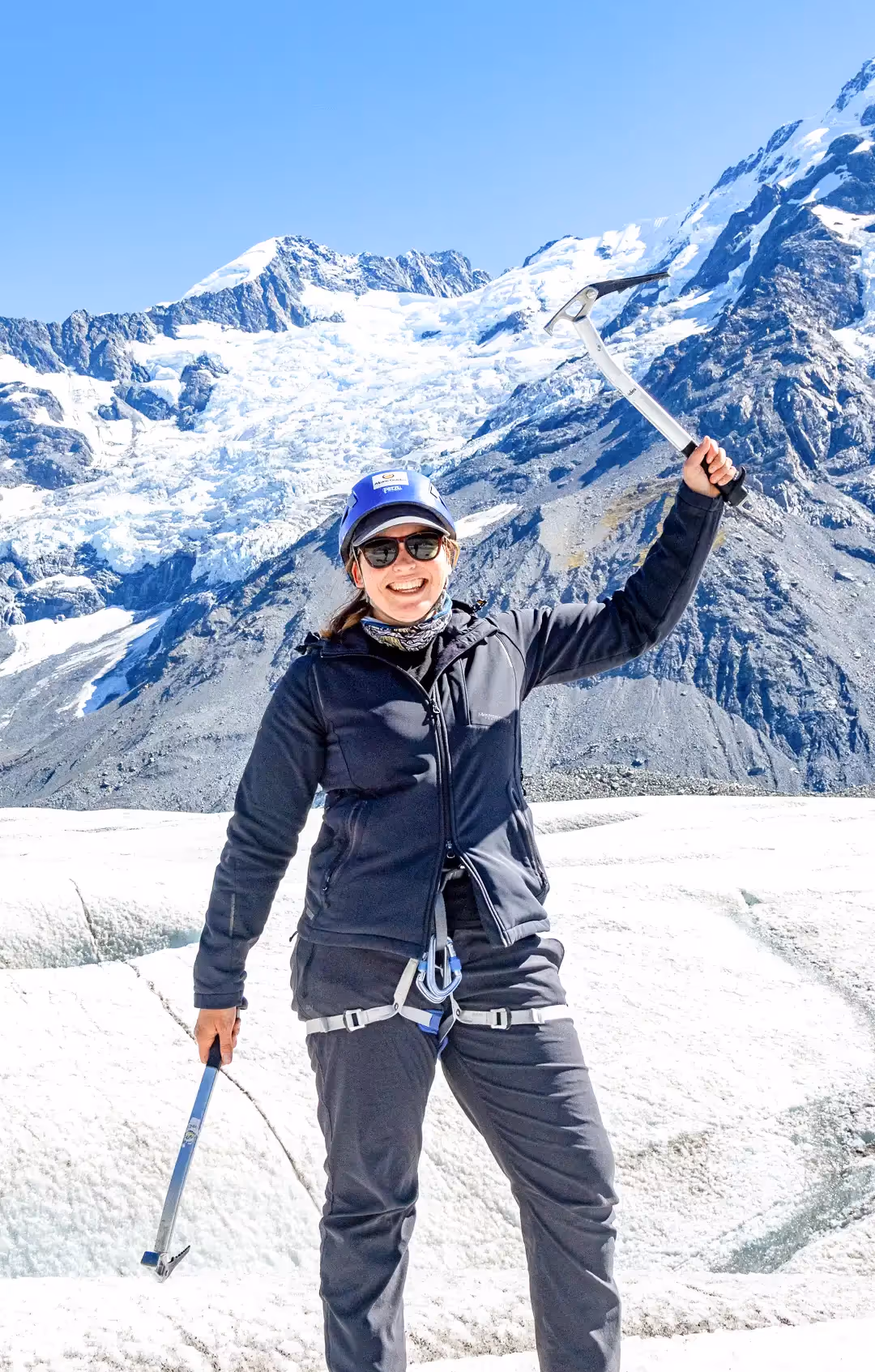 Guest raising ice axe on glacier, enjoying the moment