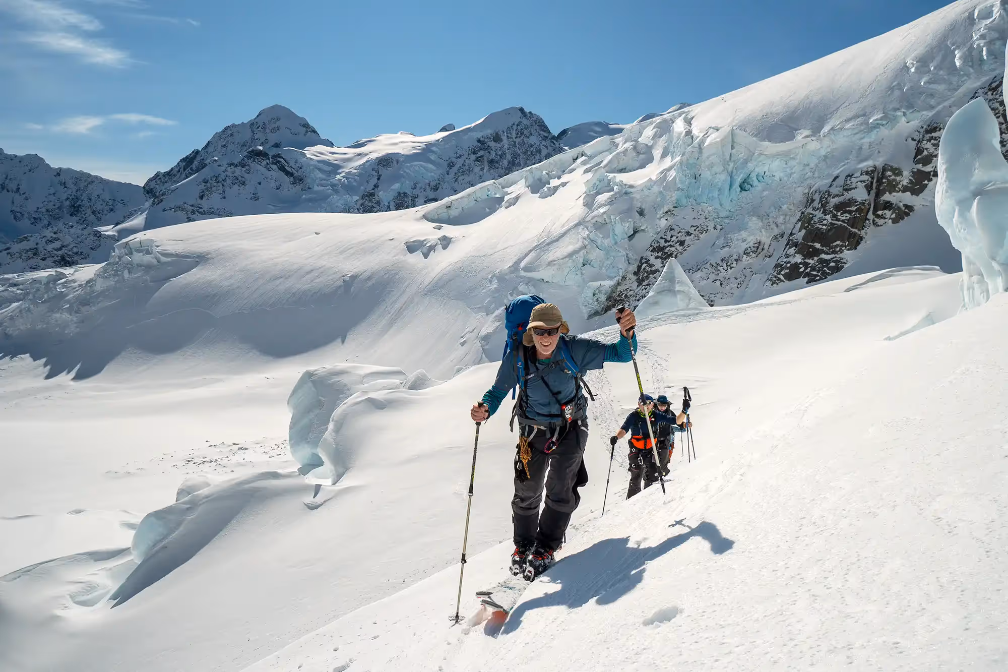 Private guiding participants ascending a snowy slope on skis using skins