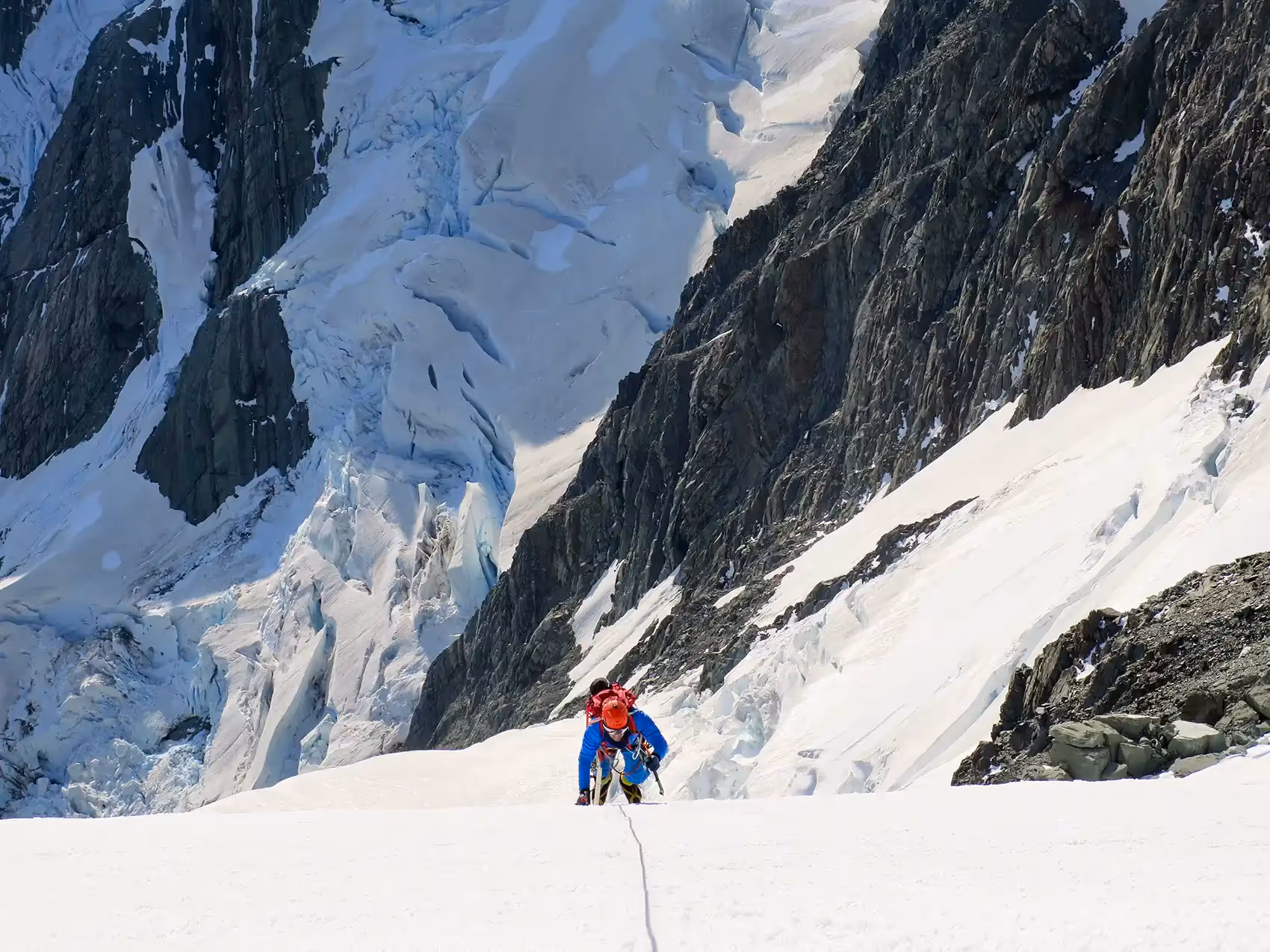 Technical Mountaineering Course participant ascending steep snowy slope with ice axe and crampons