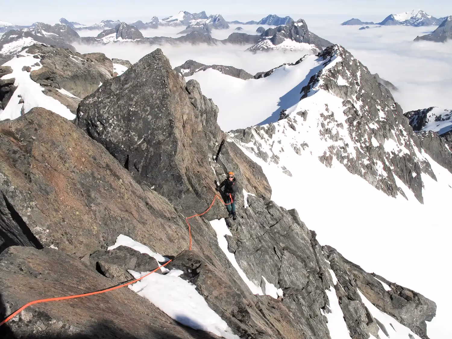 Climber ascending rock face on fixed rope