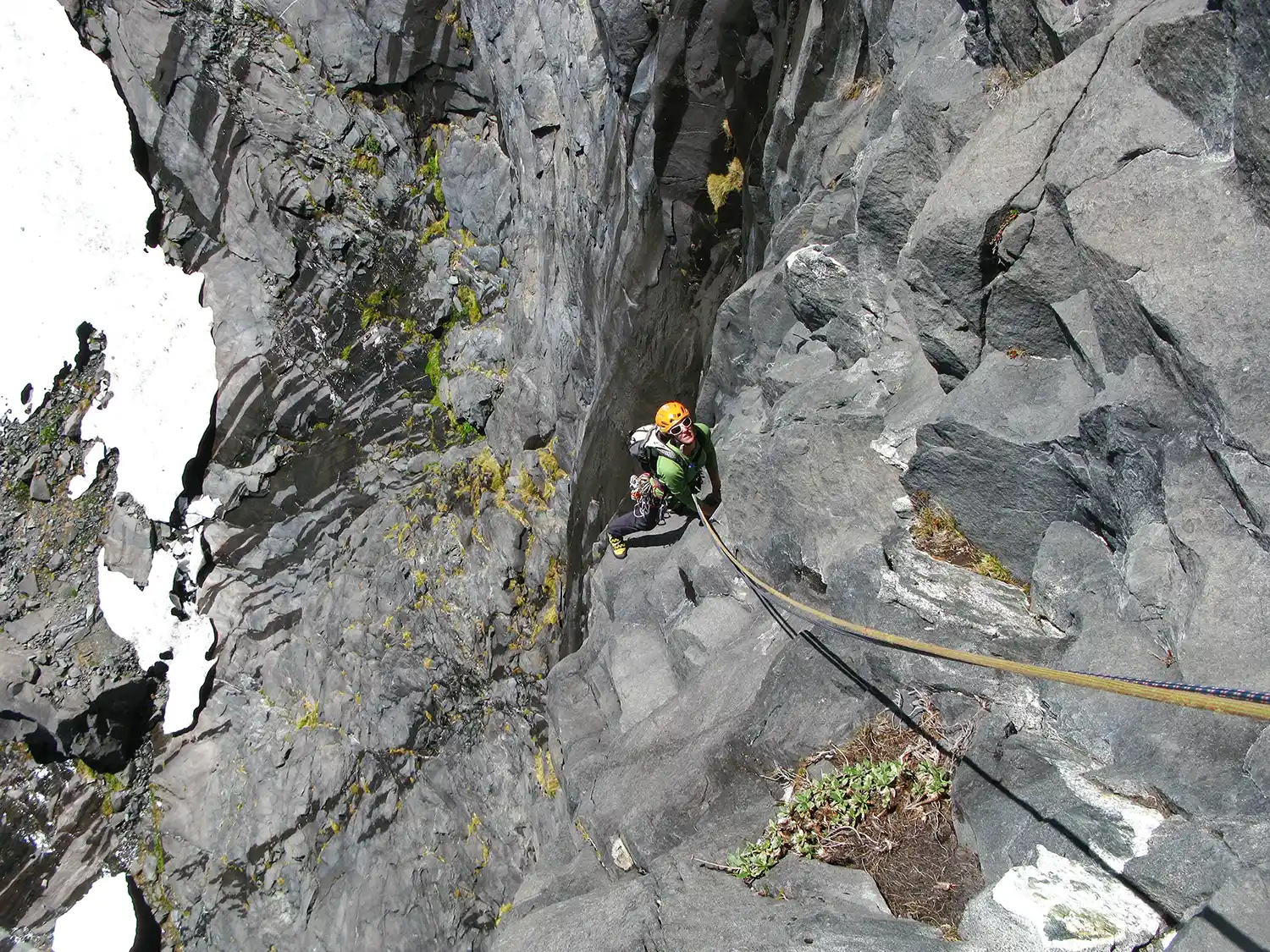 Climber ascending rock face on fixed rope
