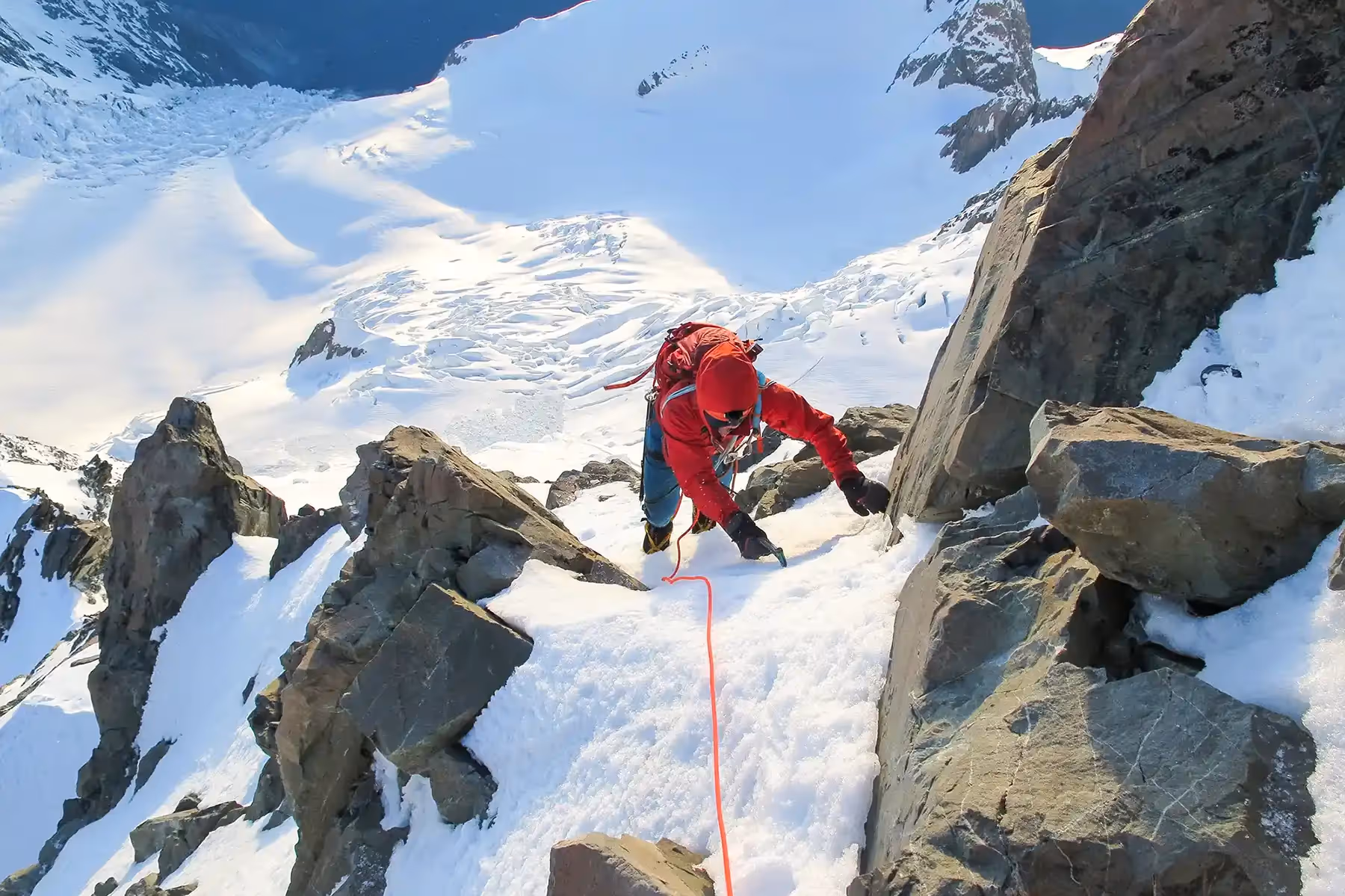 Guest ascending snowy slope using ice axe and crampons