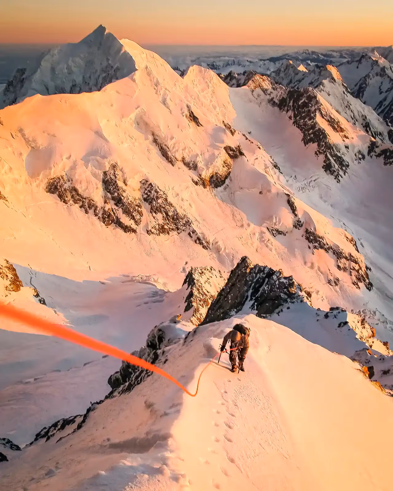 Aoraki Mount Cook climber roped up traversing snowy ridge with ice axe and crampons