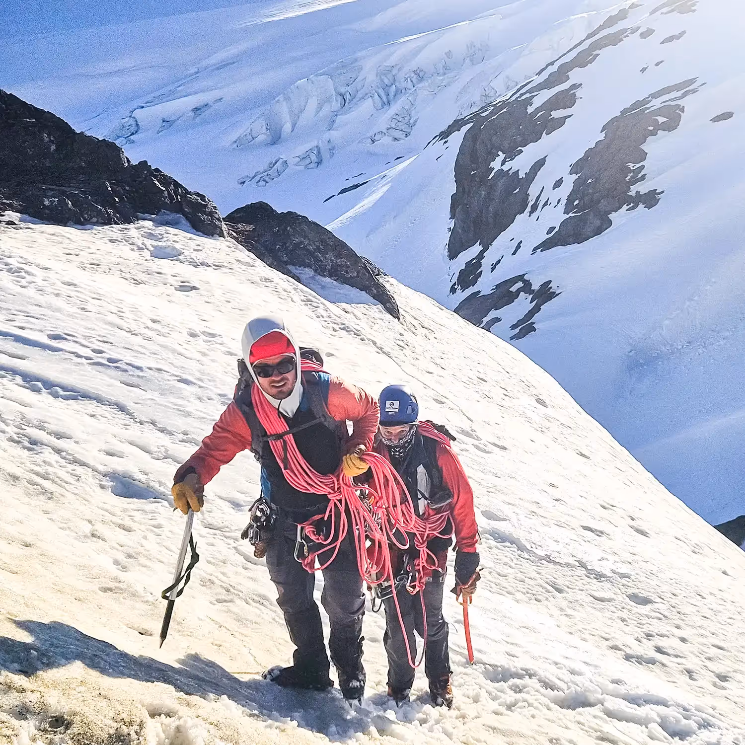 Roped climbers walking through snowy slope