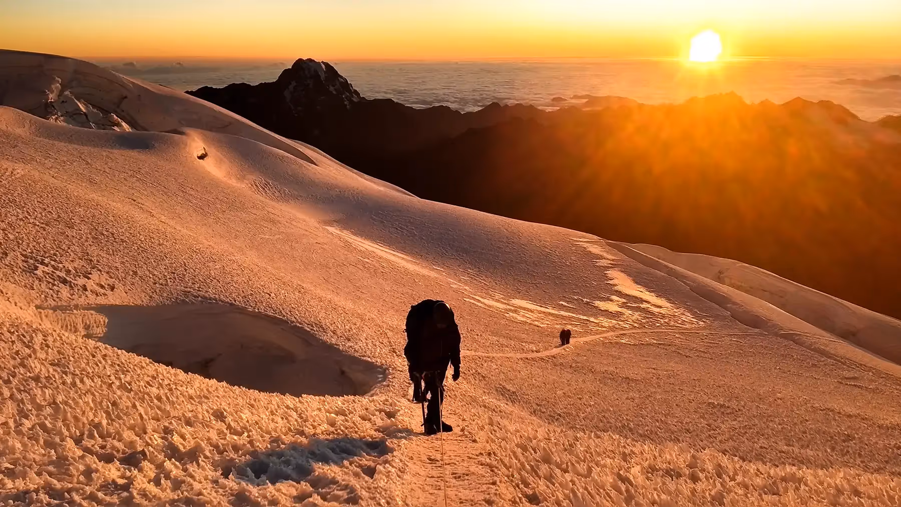 Alpinismo Boliviano climber traversing snowy slope at sunrise