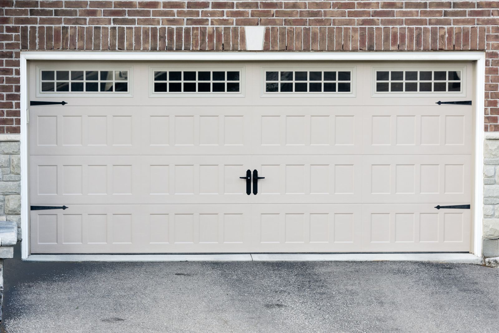 Modern beige Stamped Shaker garage double door with decorative windows and black hardware, newly installed for residential garage door replacement.