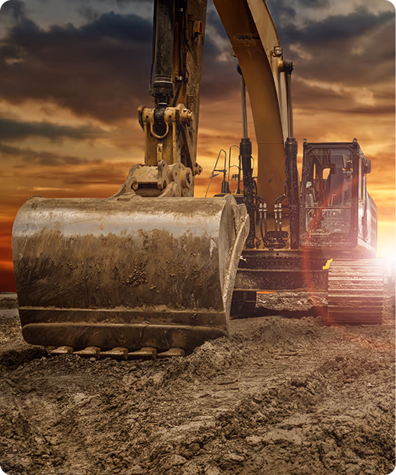 Excavator with a large bucket on muddy ground during a sunset.