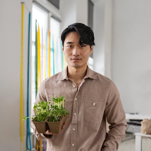 Professional grower holding a tray of seedlings in a modern greenhouse facility