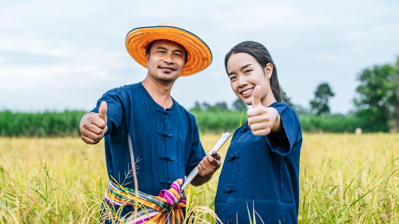 Smiling male and female farmers standing in a field, representing a successful modern agribusiness partnership