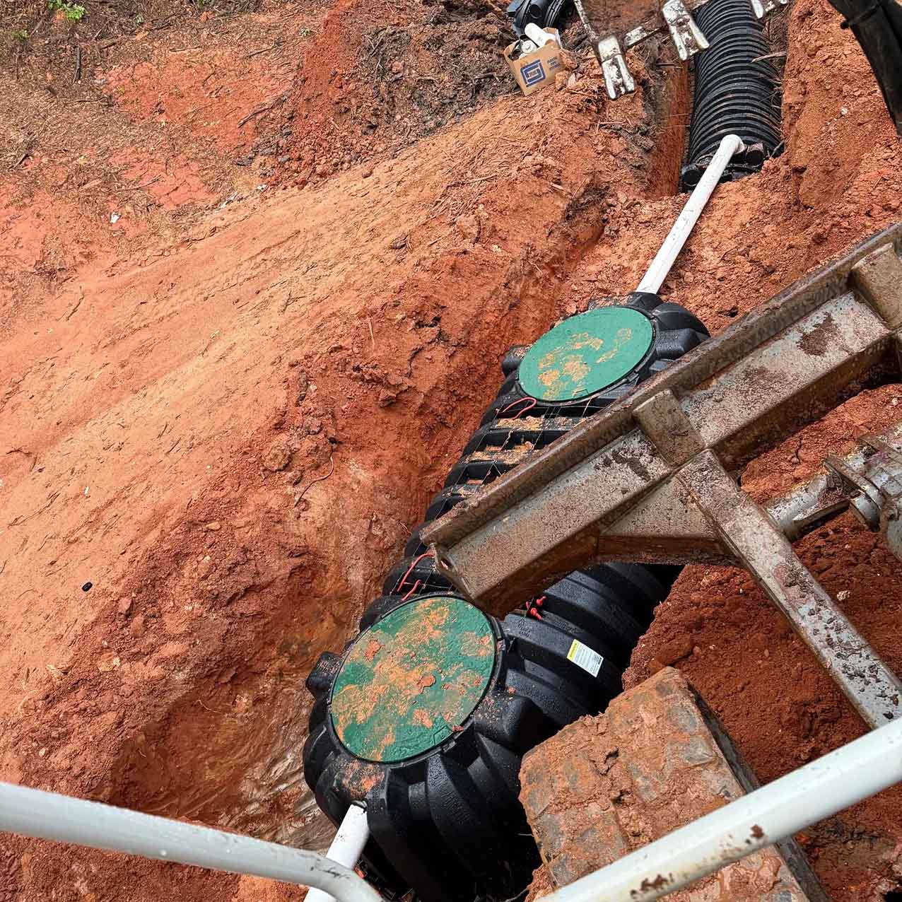 Septic tank installation in north Georgia; tank in ground, covered by the infamous red clay of Georgia.