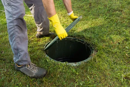 Septic tank inspections in north Georgia; man lifting cover to inspect system.