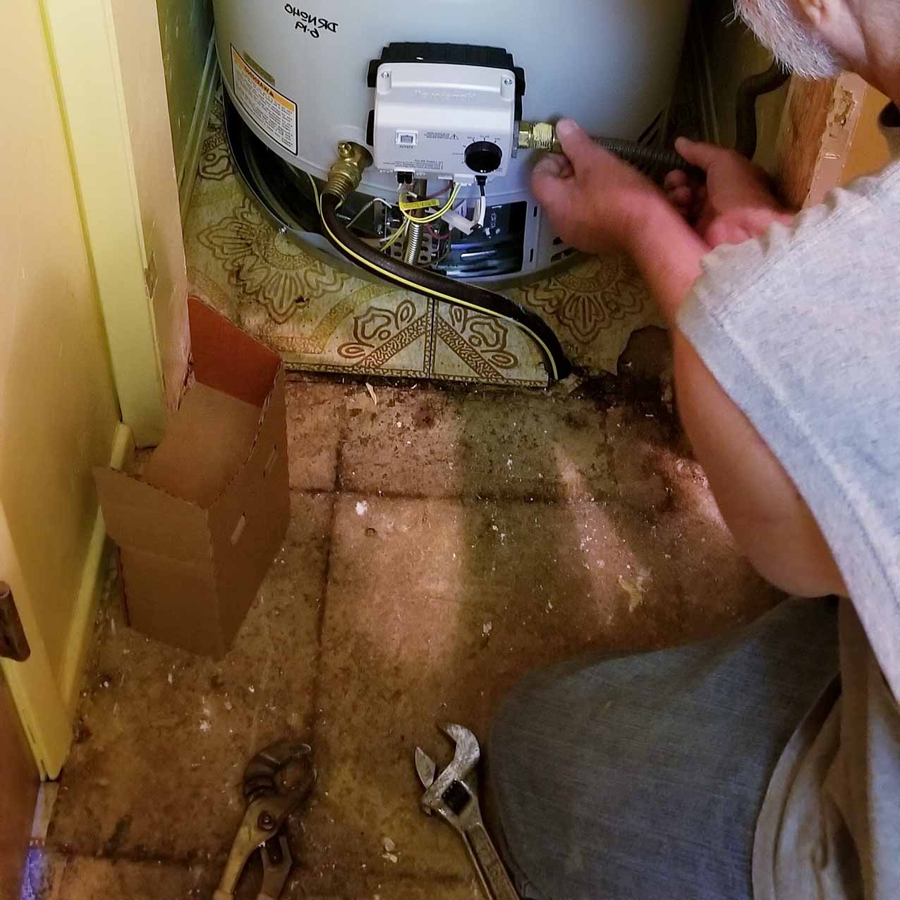 Water heater leak repair in north Georgia; man repairing water heater, as seen from over his shoulder.