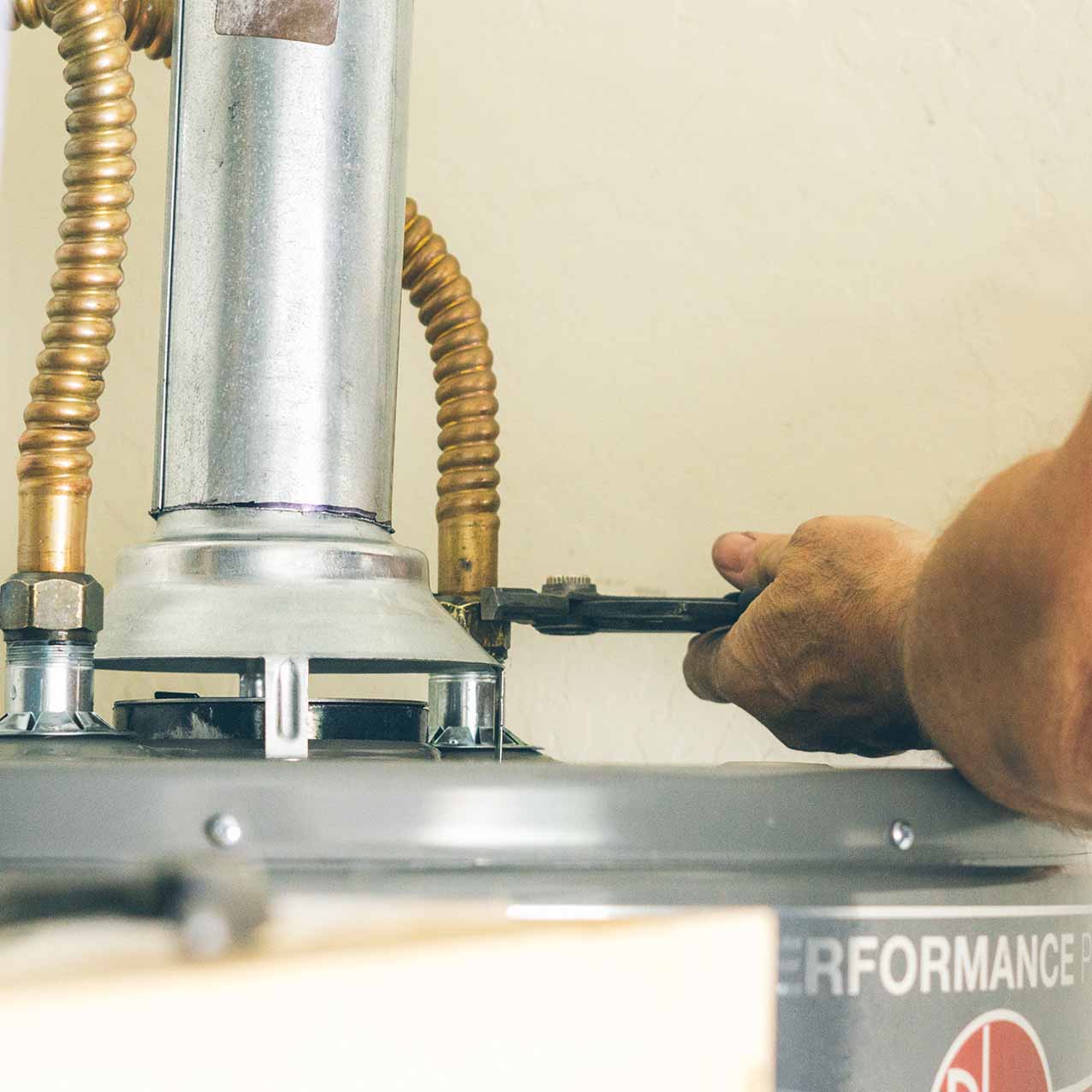 Water heater maintenance in north Georgia. Man tightening a pipe with a wrench.