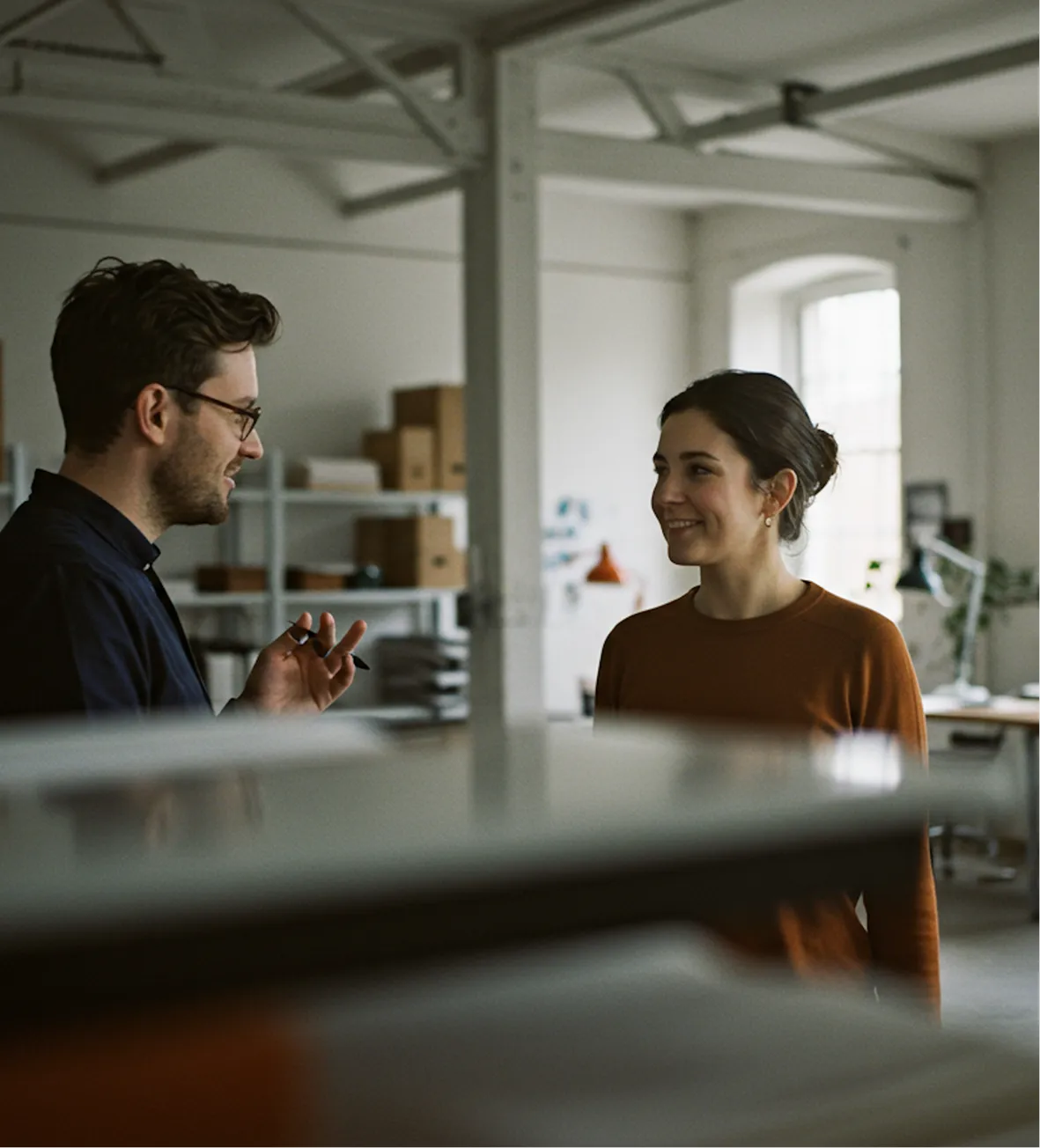 Two people talking during a meeting in a bright modern office space.
