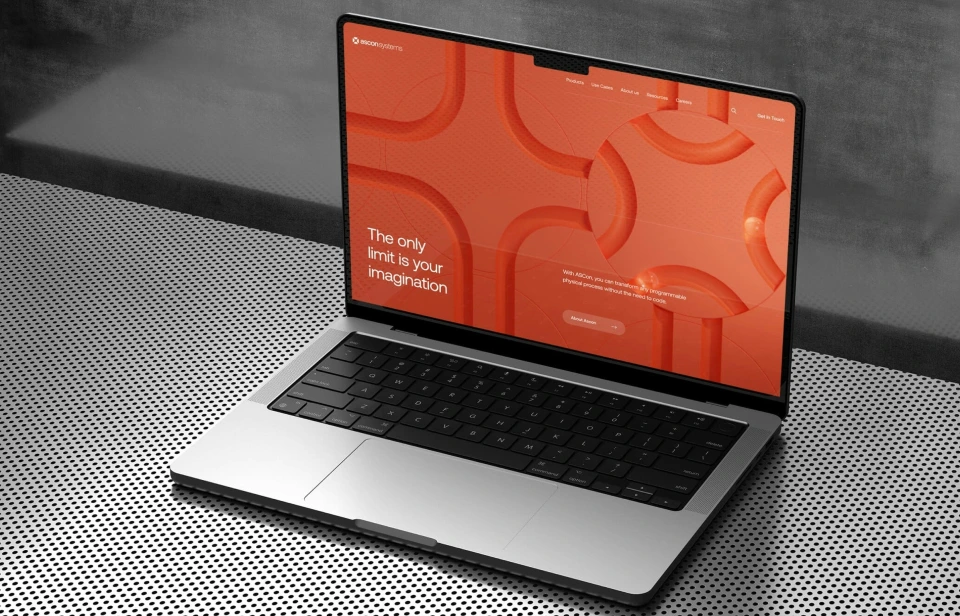 Open laptop on a perforated metal surface displaying a red website homepage with the text 'The only limit is your imagination.'