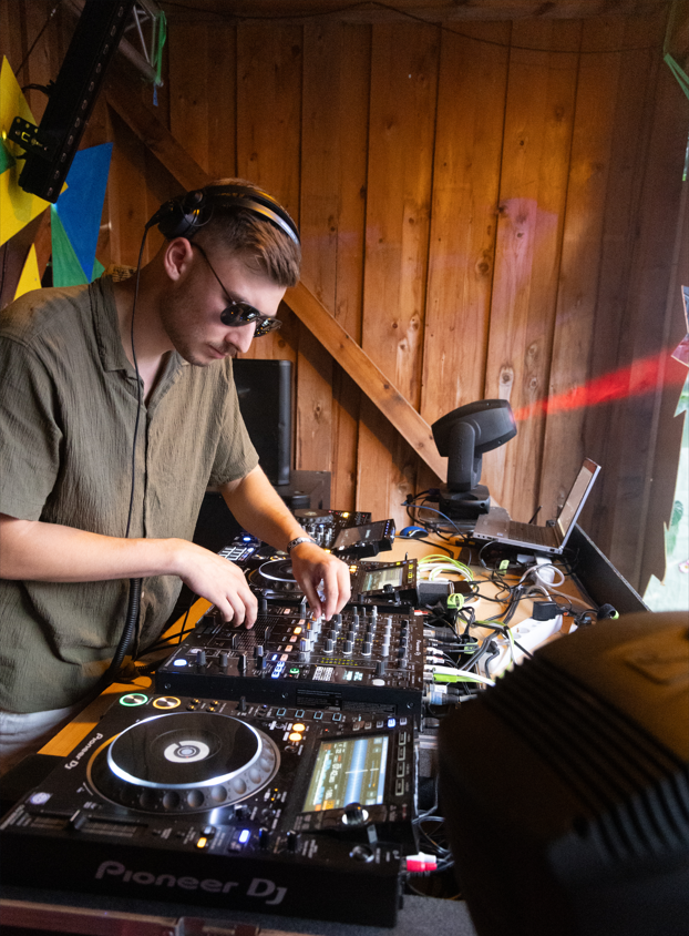 DJ Glen Haens beim Mixen an einem DJ-Pult vor einer Holzwand