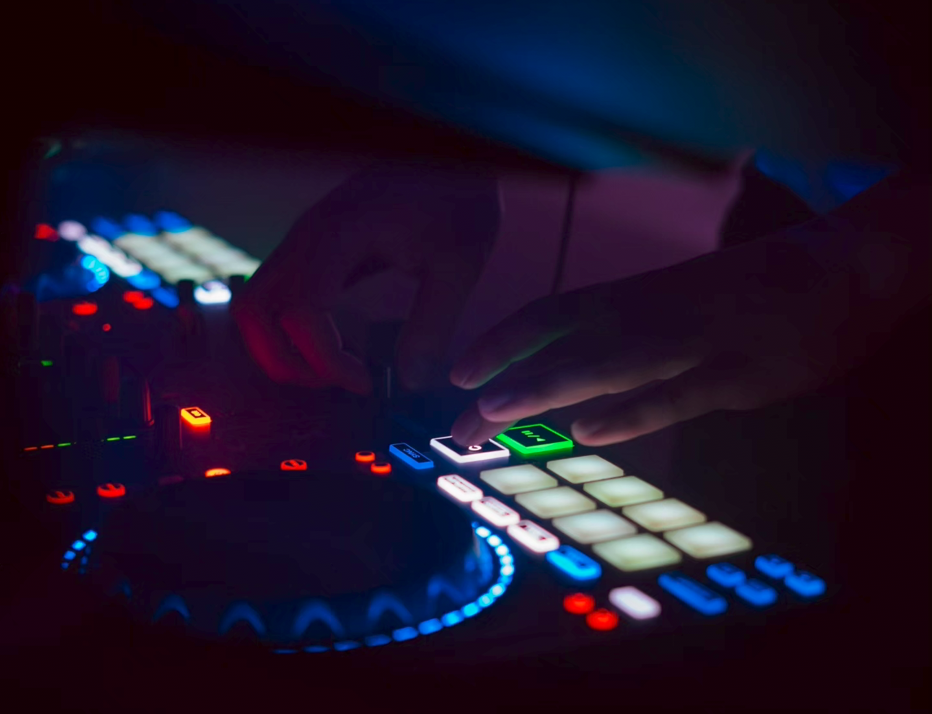 Dunkle Nahaufnahme einer Hand an einem beleuchteten DJ-Controller