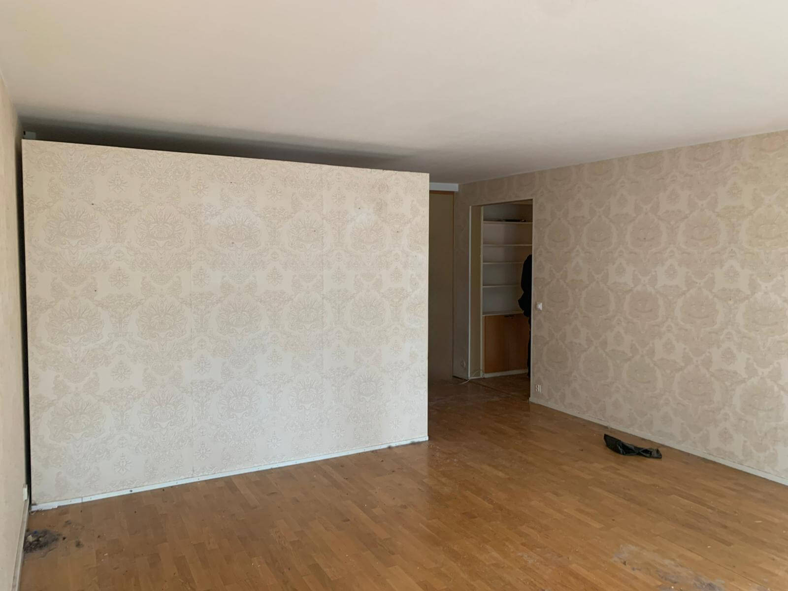 Tyhjä huone, jossa on parkettilattia, tapetoidut seinät ja avoin vaatehuone.